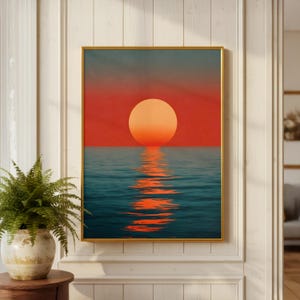 以下が含まれることがあります： 海に沈む夕日を描いたフレーム入りアートプリント。このアートワークは、ターコイズブルーの水面に沈む大きなオレンジ色の太陽と、太陽の反射を特徴としています。空は赤から濃い青に変化します。フレームは金色です。