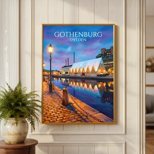 Op de afbeelding: Een ingelijste muurkunstprint met een schemeringtafereel in Göteborg, Zweden. De afbeelding toont een geplaveid pad, een verlichte lantaarnpaal, een kanaal dat een gebouw met een puntdak weerspiegelt, en een paars-blauwe lucht met de tekst GOTHENBURG SWEDEN.