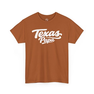 May include: A white ceramic mug with a black handle and the text "But First, Coffee" in a black, handwritten-style font. The mug is on a white surface.