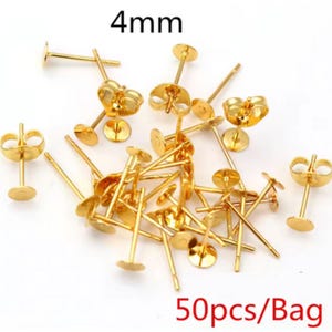 May include: A collection of gold-colored earring posts with flat pads, each measuring 4mm in diameter. The image shows multiple earring posts, with the text "50pcs/Bag".
