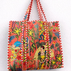 Könnte beinhalten: Eine gesteppte Tragetasche mit einem lebendigen Blumenmuster und einem von Frida Kahlo inspirierten Druck. Die Tasche hat einen roten Hintergrund mit grünen, gelben und blauen botanischen Elementen. Die Griffe und Kanten sind mit rot-weißen Streifen versehen.