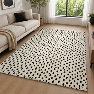 May include: A rectangular area rug featuring a cream-colored base with a dense, repeating pattern of small, irregular black dots distributed across the entire surface, creating a high-contrast visual texture for floor coverage.