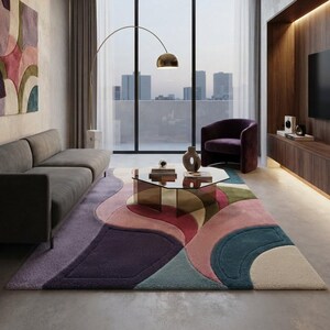 May include: A large area rug featuring a multi-colored abstract pattern with curved shapes in shades of purple, pink, teal, and cream. The rug has a textured, tufted surface and covers a significant portion of the floor in a living room setting.