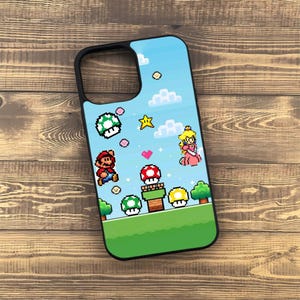 May include: Black phone case featuring a pixelated design of a video game scene with Mario, Princess Peach, mushrooms, and a blue sky background. The case has a black border and a green landscape.