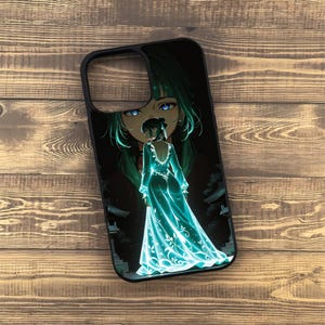 May include: Black phone case featuring an anime-style illustration of a woman in a flowing, turquoise gown. The artwork includes a large face with green hair and blue eyes. The case has a black border and is set against a wooden background.