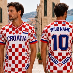 Puede incluir: Una camiseta de f&uacute;tbol de Croacia a cuadros rojos y blancos con la palabra "CROATIA" en azul en el pecho. La camiseta tiene cuello en V, ribetes azules y rojos y la bandera croata en el pecho. La parte trasera de la camiseta tiene el n&uacute;mero 10 en azul.