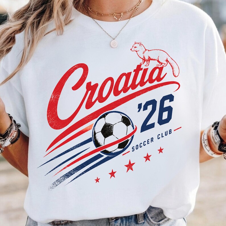 May include: A white t-shirt featuring a graphic design with the red text Croatia, a black and white football, the blue text '26 Soccer Club, a small animal illustration, and five red stars with blue and red motion lines across the front.