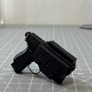 May include: A set of three ceramic mugs with a speckled, cream-colored glaze. Each mug features a different hand-painted design: a blue and green leaf, a yellow flower, and a red berry. The mugs have a simple, rounded shape.