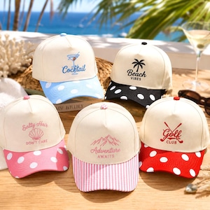 May include: Five baseball caps with cream-colored crowns and patterned brims. Designs include a blue cocktail, a black palm tree with Beach Vibes, a pink seashell with Salty Hair Don't Care, pink mountain lines with Adventure Awaits, and red golf clubs.