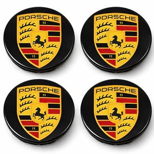 Könnte beinhalten: Vier schwarze Porsche-Radnabenabdeckungen. Jede Kappe zeigt das Porsche-Emblem: ein schwarzes Pferd auf einem gelben Schild mit roten und schwarzen Streifen und dem Wort "PORSCHE" darüber. Die Zahl "11" ist ebenfalls sichtbar.