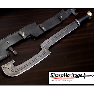 May include: A steel falchion sword with a distinct hooked blade profile, a black handle, and a brass pommel. The sword is accompanied by a black leather sheath featuring brass rivets and straps. The text SharpHeritage Born at the Forge is visible.