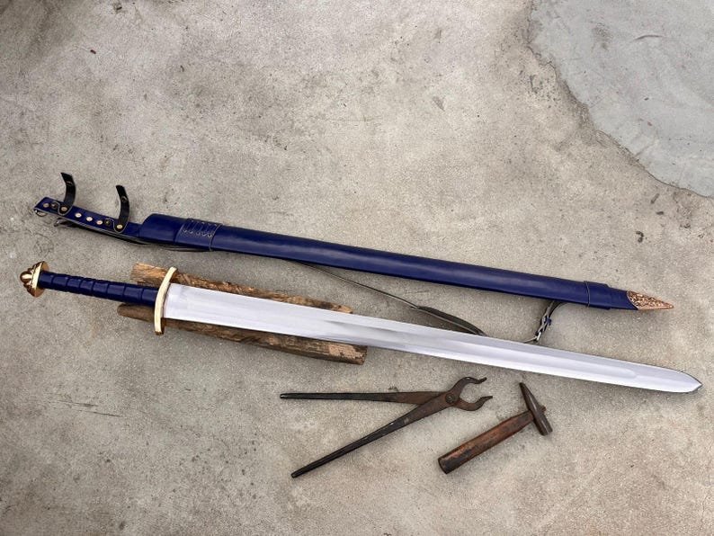May include: A double-edged steel sword with a blue leather-wrapped grip, a gold-colored pommel and crossguard, and a matching blue leather scabbard with gold-colored metal fittings. A pair of iron blacksmith tongs and a small hammer are included.