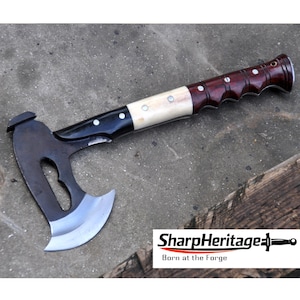 May include: A small axe with a dark metal head and a polished, multi-toned handle. The handle features sections of dark wood, bone-colored material, and black, with decorative rivets. The axe blade is silver and the text "SharpHeritage" is visible.