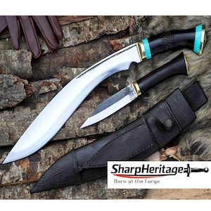 Puede incluir: Dos cuchillos con hojas curvas y mangos de madera oscura, acentuados con oro y turquesa. También hay un cuchillo más pequeño y una funda de cuero negro. La imagen incluye el texto "SharpHeritage - Born at the Forge."