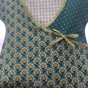 May include: A green and white patterned fabric with a green gingham fabric insert. The fabric has a green ribbon tied around it.