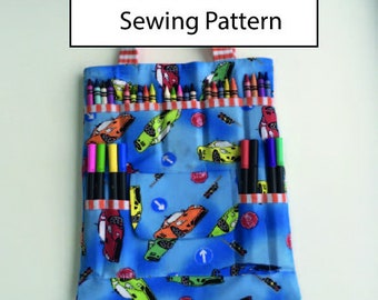 May include: A blue fabric tote bag with a red and white striped handle. The bag has a pocket on the front and is filled with crayons and markers. The bag has a print of cartoon cars and traffic signs. The text "Sewing Pattern" is printed on a white rectangle above the bag.