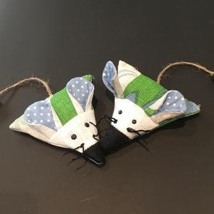 Może przedstawiać: Dwie ręcznie robione myszy z tkaniny w zielonym, niebieskim i białym wzorze. Myszy mają czarne filcowe nosy i wąsy.