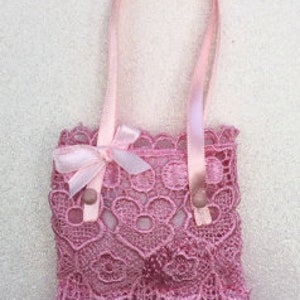 May include: A small pink lace bag with a pink ribbon bow and two pink ribbon handles.