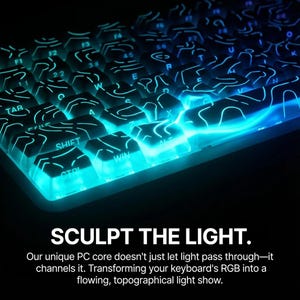 Puede incluir: Primer plano de un teclado retroiluminado con teclas brillantes azules y turquesas. Las teclas están iluminadas con un diseño de luz topográfico. El texto "SCULPT THE LIGHT" se muestra en la parte inferior de la imagen.