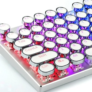 May include: Close-up of a mechanical keyboard with round, white keycaps and silver trim. The keys are backlit with a gradient of purple, pink, and blue. The keyboard has a retro typewriter aesthetic.