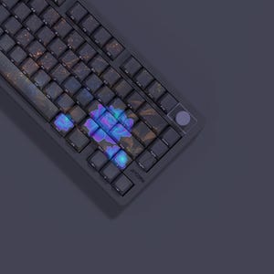 Könnte beinhalten: Eine dunkelgraue mechanische Tastatur mit individuellen Tastenkappen. Die Tastenkappen weisen ein Blumendesign mit blauen und violetten Farbtönen auf. Die Tastatur hat eine runde, violette Taste und die Marke "JAYCOMA" ist sichtbar.