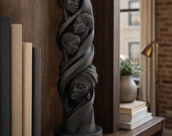 Könnte beinhalten: Dunkelgraue Skulptur mit vier übereinander angeordneten Frauengesichtern in einem wirbelnden Design. Die Skulptur mit matter Oberfläche steht auf einem dunklen Holzregal. Bücher sind im Hintergrund zu sehen. Dekorationsartikel.