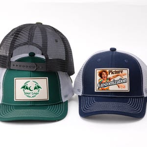 May include: Two trucker hats. One is dark green with a white mesh back and a patch with a logo. The other is navy blue with a white mesh back and a patch that says "Picture Customization".