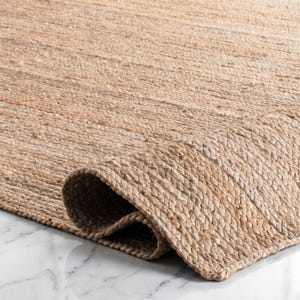 Könnte beinhalten: Ein hellbrauner Teppich aus geflochtenen Naturfasern. Der Teppich weist eine dichte, gewebte Textur mit einem sichtbaren Spiralmuster auf. Eine Ecke des Teppichs ist umgeschlagen und zeigt den dicken, geschichteten Aufbau des geflochtenen Materials.