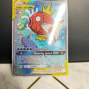 May include: A holographic Magikarp & Wailord GX Tag Team trading card. The card features a red Magikarp and a blue Wailord with water effects. The card has a yellow border and the text "Super Splash" and "Towering Splash GX".
