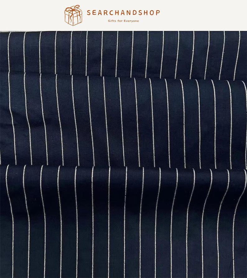 May include: A dark navy blue fabric featuring a repeating pattern of thin, vertical white pinstripes. The textile has a visible woven texture and is displayed with soft folds. The top of the image includes the text SEARCHANDSHOP Gifts for Everyone.