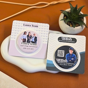 May include: Two business card magnets. One features the text "Laura Team" and a photo of three people. The other features the text "Will Jack" and a photo of a man. Both cards include phone numbers.