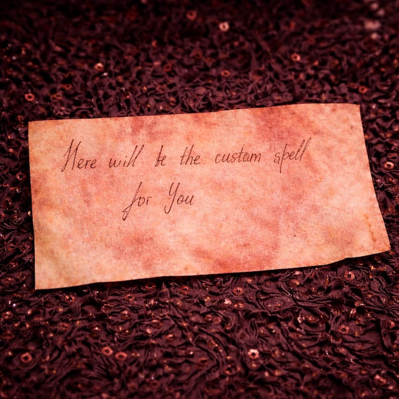 May include: A rectangular piece of aged paper with handwritten text in brown ink. The text reads "Here will be the custom spell for You". The paper has a reddish-brown hue and is set against a dark, textured background.