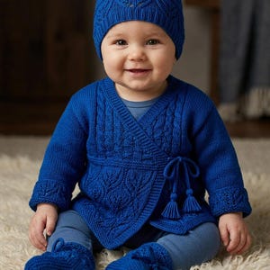Pode incluir: Um conjunto de malha azul-real composto por um casaco cruzado de manga comprida com textura de padrão de folhas e fecho lateral com borlas, um gorro a condizer com rebordo canelado e um par de botins de malha sobre leggings azuis.