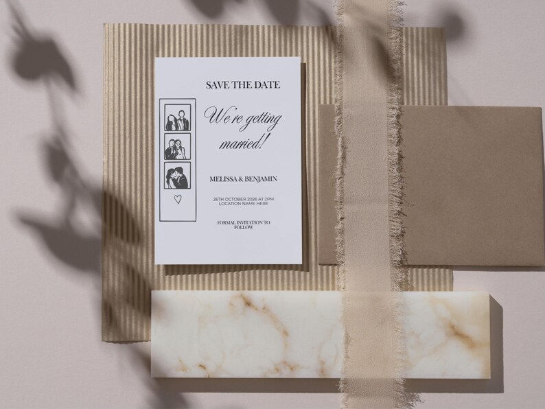 May include: A wedding invitation suite featuring a white card with the text "Save the Date" and "We're getting married!" with photo booth style images. The suite includes a brown envelope, ribbon, and a marble accent.