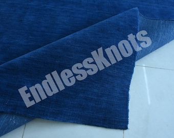 Könnte beinhalten: Ein tiefblauer Teppich mit einer strukturierten, gewebten Oberfläche. Eine Ecke des Teppichs ist umgeschlagen und gibt den Blick auf die Unterseite frei, die einen etwas helleren Blauton aufweist. Der Text EndlessKnots liegt diagonal über dem Teppich.