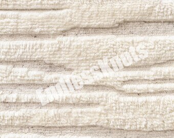 Könnte beinhalten: Ein cremefarbener Stoff mit einem hochflorigen, getufteten horizontalen Streifenmuster und einer strukturierten, erhabenen Oberfläche. Das Wort "Knots" ist in einer halbtransparenten weißen Schrift zu sehen.