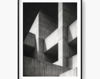 Op de afbeelding: Zwart-wit architectuurprint met een abstracte compositie van betonnen structuren. De afbeelding toont geometrische vormen en schaduwen, wat een moderne en minimalistische esthetiek creëert. Het kunstwerk is ingelijst in een zwarte lijst.