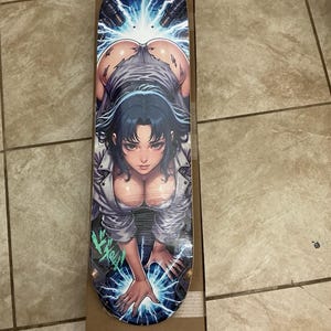 May include: A skateboard deck featuring a graphic illustration of a dark-haired character in a white shirt and torn clothing, positioned over a blue electrical energy effect with lightning bolts emanating from the top and bottom of the board.