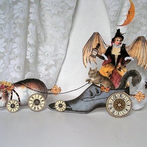 May include: A whimsical, handmade, papercraft sculpture of a winged fairy riding a clockwork shoe, pulling a guinea pig in a carriage with clockwork wheels. The fairy is holding a bottle and is accompanied by a squirrel.