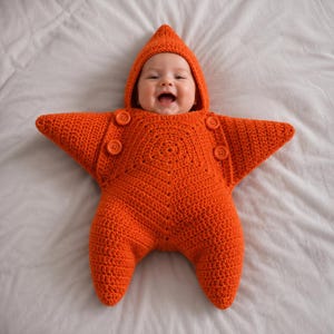 May include: A bright orange crocheted star-shaped bunting for an infant. The garment features a pointed hood, five distinct points, and four matching orange buttons arranged symmetrically on the front chest area to secure the piece.