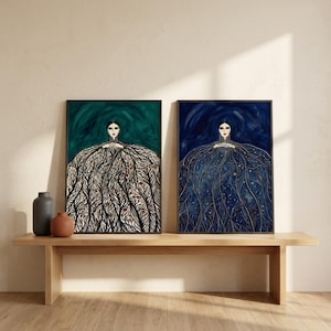 Pode incluir: Duas impressões artísticas emolduradas. Uma apresenta uma figura com fundo verde escuro e uma forma de vestido feita de padrões de árvores em preto e branco. A outra tem um fundo azul escuro com uma figura em forma de vestido com detalhes dourados.