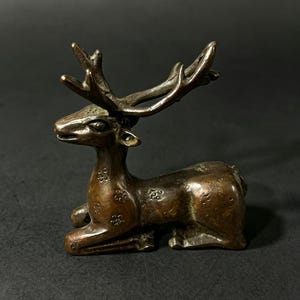 Puede incluir: Una taza de cerámica blanca con un asa negra y el texto "But first, coffee" en un estilo manuscrito. La taza está sobre una superficie blanca. La taza mide 10 cm de alto.