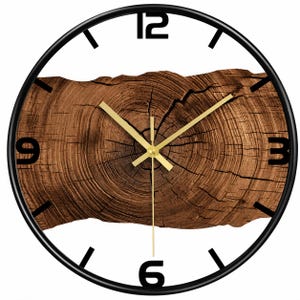 Könnte beinhalten: Eine runde Wanduhr mit einem dünnen schwarzen Rahmen und einem weißen Zifferblatt, das ein zentrales horizontales Holzmaserungsmuster aufweist. Die Uhr hat schwarze Ziffern an den Positionen 12, 3, 6 und 9, schwarze Striche für die Stunden und drei goldene Zeiger.