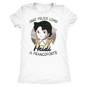 Può includere: Una t-shirt bianca a maniche corte con un'illustrazione grafica di un personaggio dai capelli scuri con un top giallo. Il testo sopra recita OGGI FELICE COME e il testo sotto recita Heidi A FRANCOFORTE in caratteri neri sul davanti.