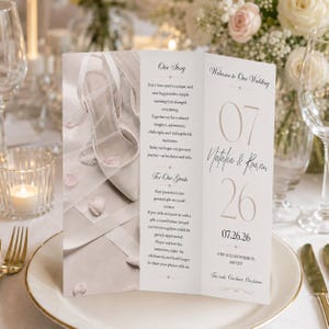 May include: A tri-fold wedding program featuring a white high-heeled shoe and veil on the left panel, with text including Our Story, For Our Guests, Welcome to Our Wedding, the names Natalia & Roman, and the date 07.26.26 printed in black and beige.