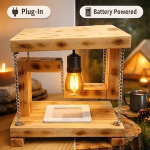 May include: A rustic wooden lamp with a warm, glowing Edison bulb suspended by chains. The lamp has a rectangular base and top, with a white frame at the base. The image shows the lamp can be plug-in or battery-powered.