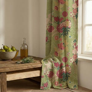 May include: A light green curtain with a floral and crane pattern. The curtain is next to a wooden table with a bowl of pears, a bottle of oil, and a bundle of herbs. The curtain has a repeating pattern of flowers and cranes.
