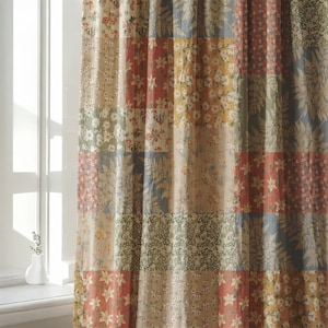 Könnte beinhalten: Ein Vorhang mit einem Patchwork-Design, das aus verschiedenen rechteckigen Stoffbahnen besteht. Jede Bahn zeigt unterschiedliche Blumen- und Pflanzenmuster in einer Farbpalette aus gedämpftem Rot, Senfgelb, Salbeigrün und sanften Blautönen.