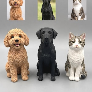 以下が含まれることがあります： 巻き毛のライトブラウンの犬、無地の黒いラブラドールレトリバー、茶色と白のトラ猫の3体の動物フィギュア。それぞれのフィギュアは座った姿勢で、詳細な質感とリアルな顔立ちが表現されています。