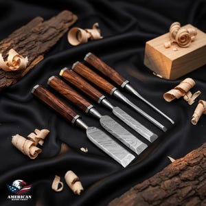 Peut inclure: Un ensemble de six ciseaux à bois avec des manches en bois foncé et des lames argentées, disposés sur une surface noire. Des copeaux de bois et un petit bloc de bois accompagnent les ciseaux. Le logo "AMERICAN HANDY CRAFT" est visible en bas à gauche.